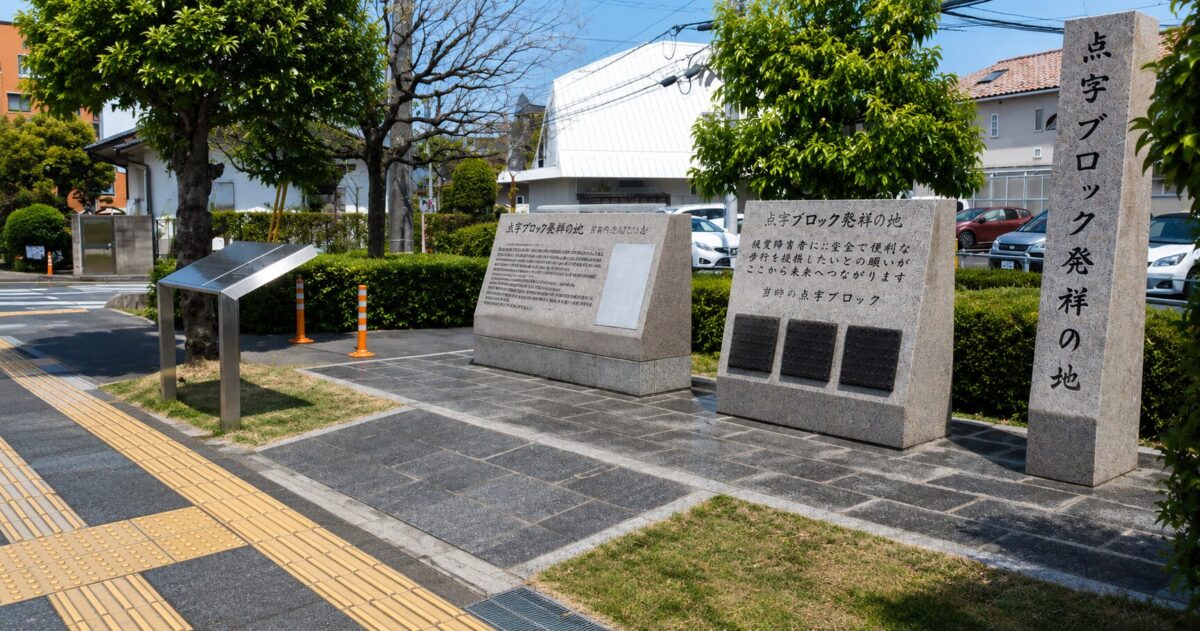 Monument marking the birthplace of tactile paving in Okayama, Japan, beside yellow tactile blocks