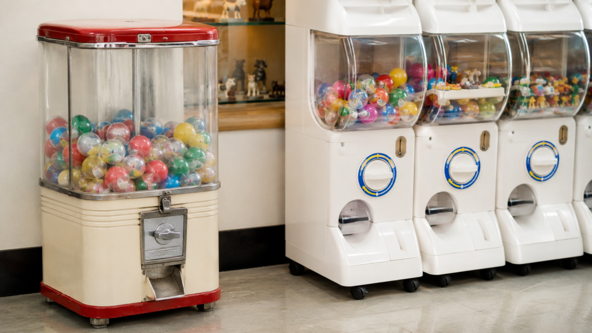 Vintage-style capsule toy machine beside modern gachapon machines in Japan