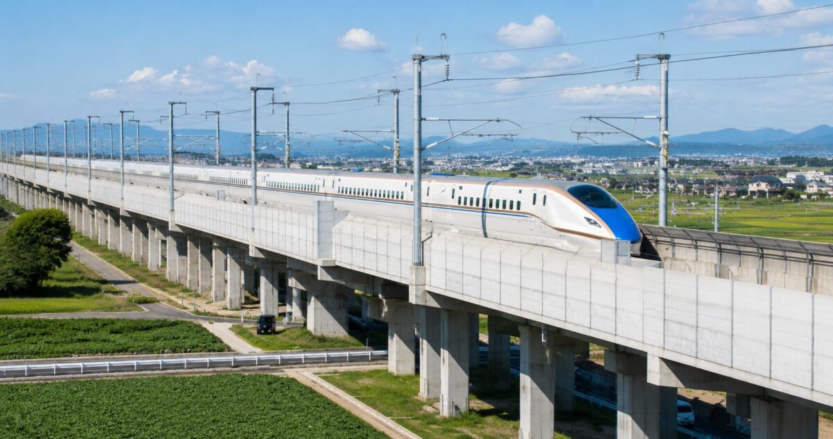 A Shinkansen bullet train traveling on an elevated railway through the Japanese countryside.