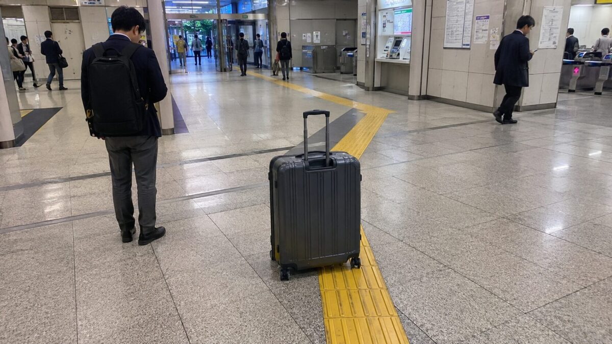 Large suitcase placed on yellow tactile paving inside a Japanese train station concourse