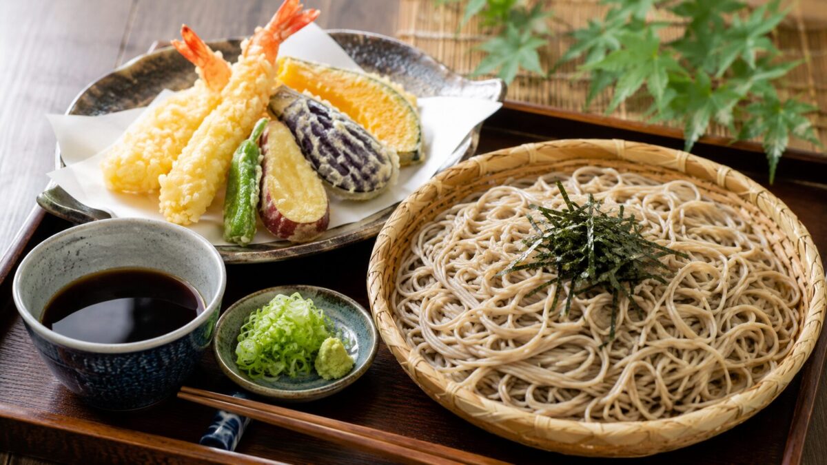 A Japanese zaru soba set meal served with assorted shrimp and vegetable tempura, dipping sauce, green onions, and wasabi.